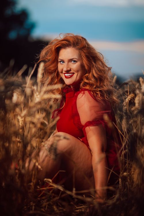 Smiling Woman in a Red Dress Sitting in a Wheat Field · Free Stock Photo
