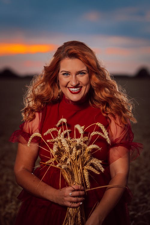 Smiling Red-haired Woman in Red Dress with Wheat Bouquet