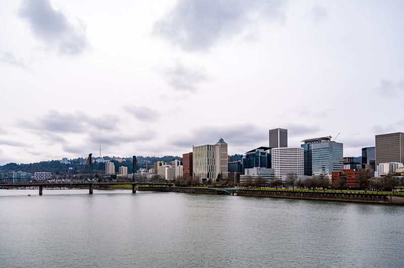Portland Oregon cityscape featuring modern buildings along the Willamette River on a cloudy day