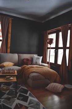 A stylish living room featuring a beige sofa, decorative pillows, and a chessboard on a wooden table.
