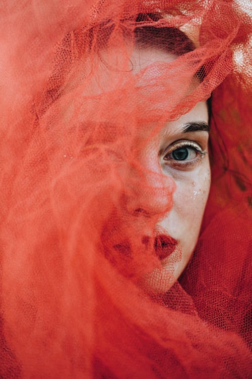Creative Portrait of a Woman with Red Tulle Fabric around Her Face