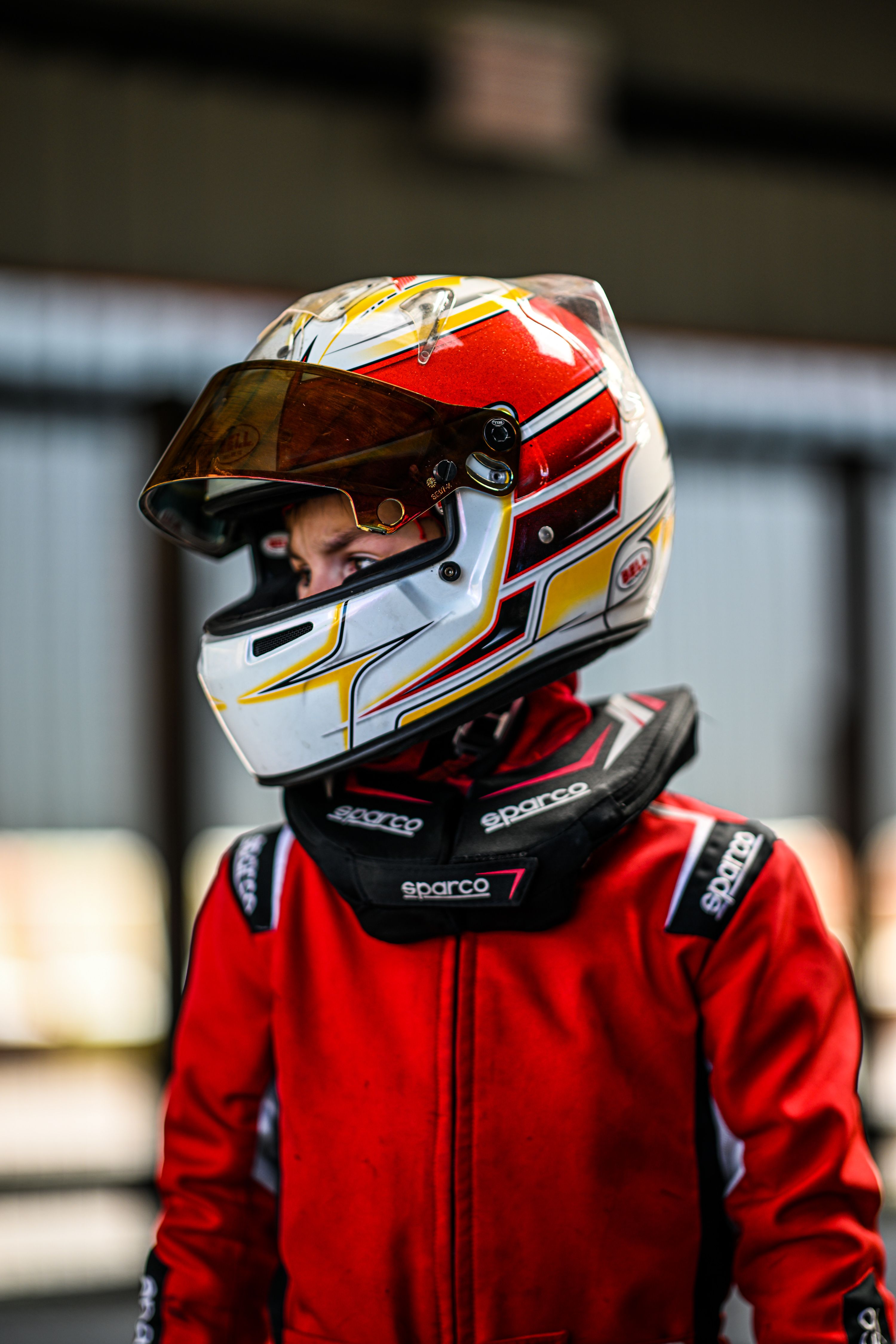 Portrait of a young racing driver in a protective helmet and suit, ready for motorsport action.