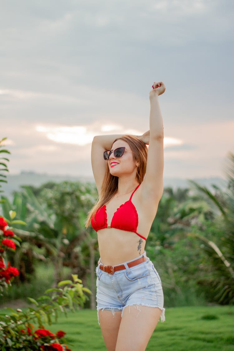 Young Woman In Bikini And Shorts Standing In The Garden