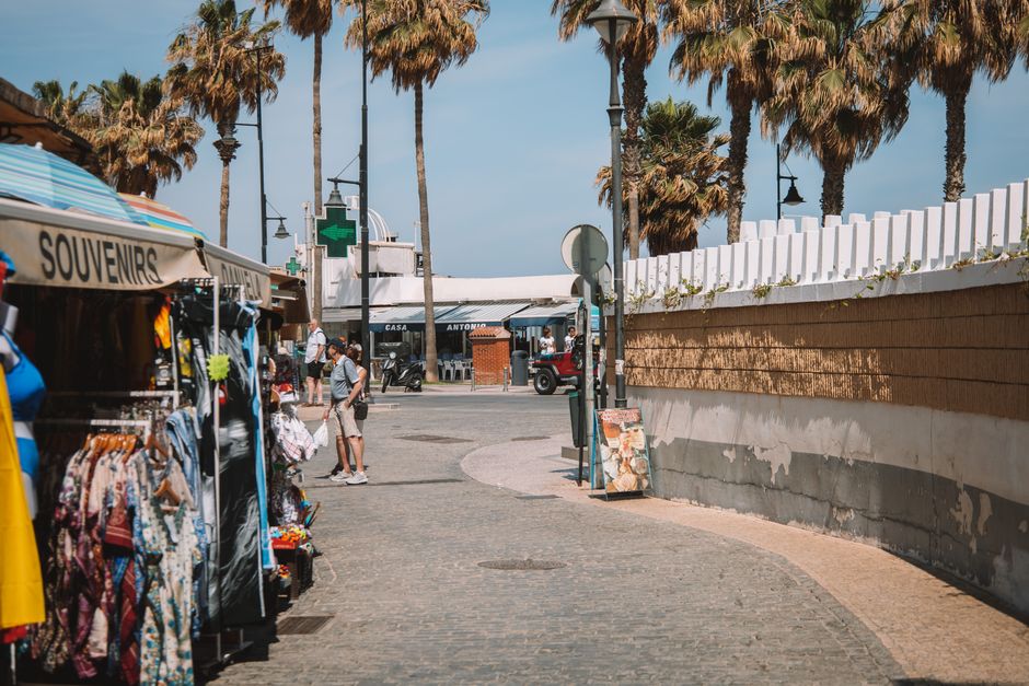 Fotomural Explora un mercado animado con puestos de souvenirs y palmeras en las calles urbanas de Málaga, España.