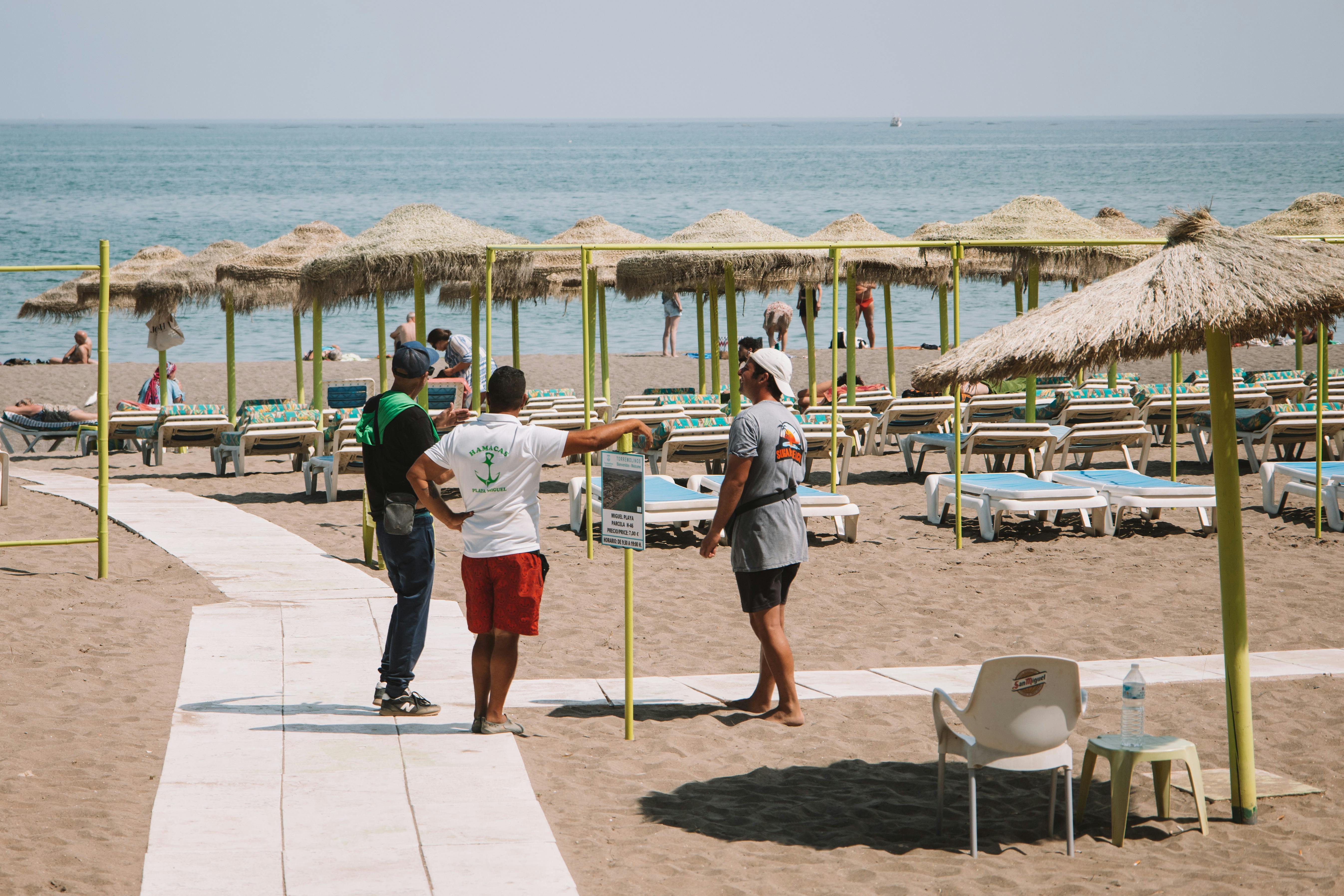 Visitors on sand with umbrellas and sun loungers on a sunny Málaga beach.