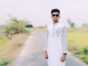 Portrait of a young man wearing sunglasses and traditional white clothing on a sunny rural road.