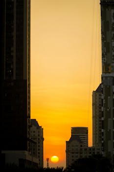 A beautiful sunset casting warm hues over a city's towering buildings, creating a dramatic urban skyline.