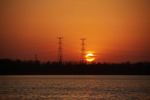 Serene sunset view in Beijing with transmission towers silhouetted against a vibrant sky.