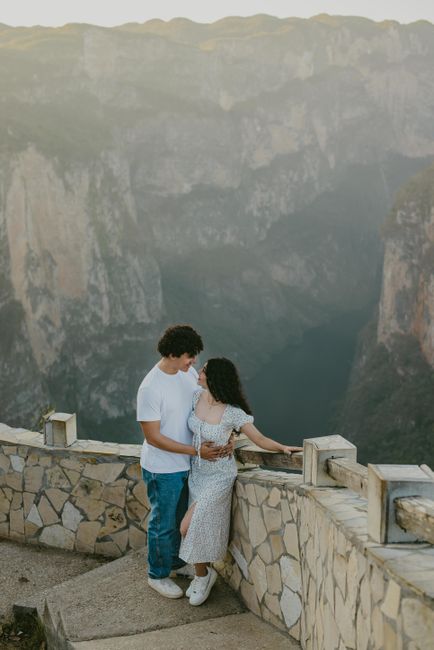 A couple embraces on a scenic cliff, capturing a romantic moment surrounded by breathtaking mountain views.