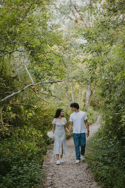 A young couple holding hands and walking along a scenic forest trail, enjoying nature's tranquility.
