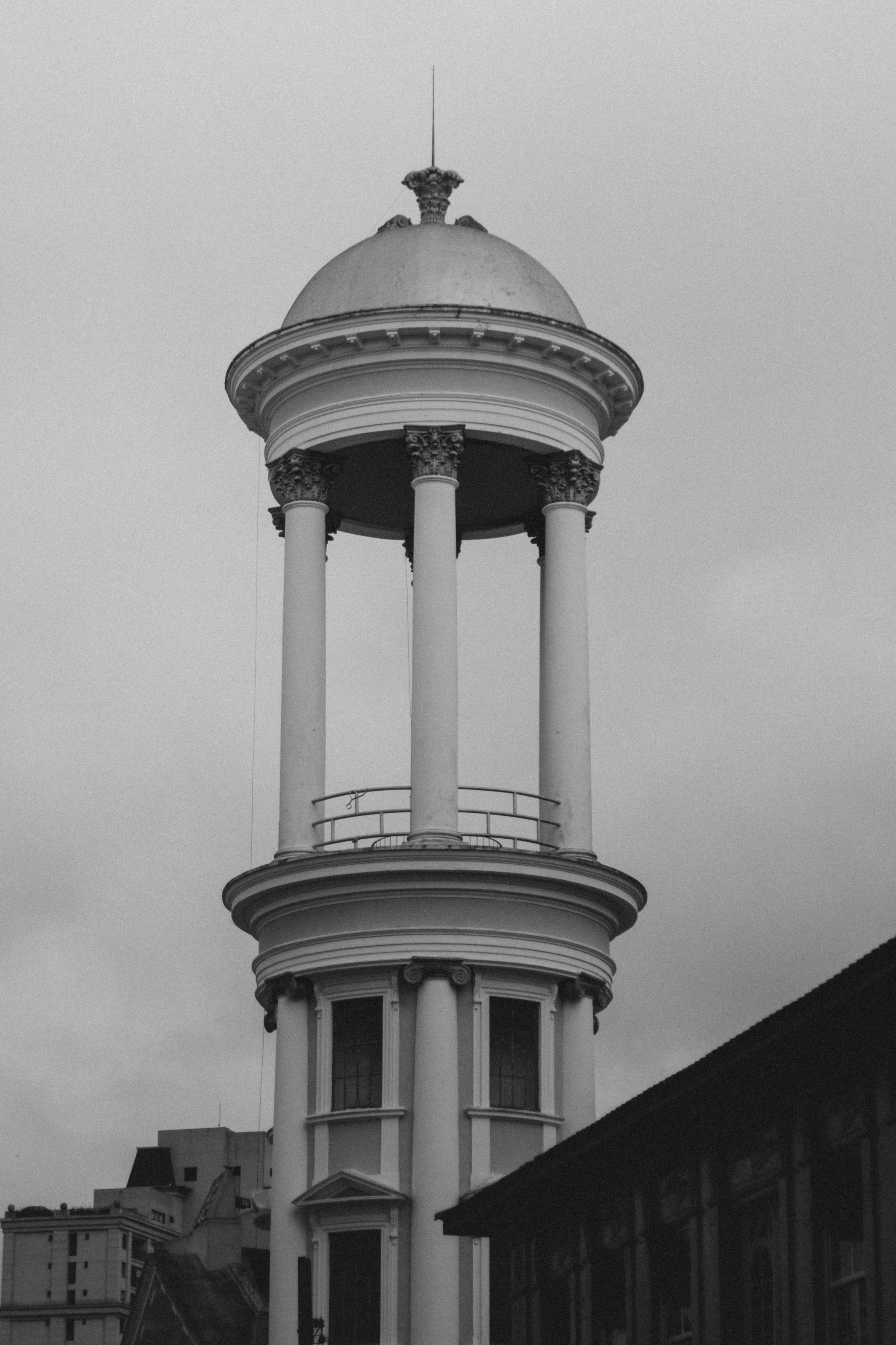 Vertical shot of a neoclassical tower with columns against a moody, overcast sky.