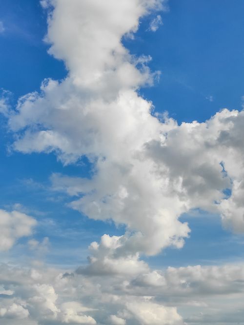 Free Serene view of fluffy white clouds against a bright blue sky, ideal for nature themes. Stock Photo