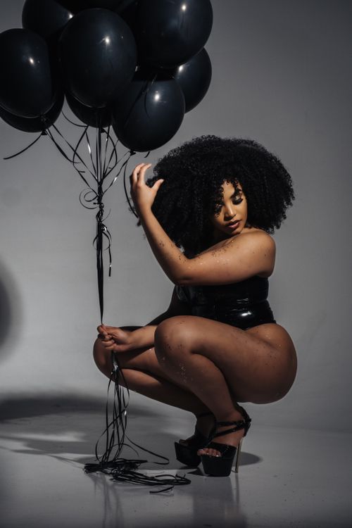 Free Curly-haired black woman posing with balloons, creating a stylish fashion statement. Stock Photo