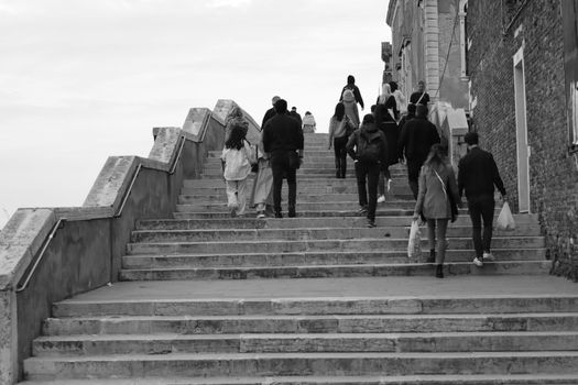 People climbing steps in Venice, Italy, captured in black and white with an urban feel.
