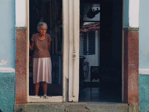 Elderly Woman Standing in the Doorway of Her House