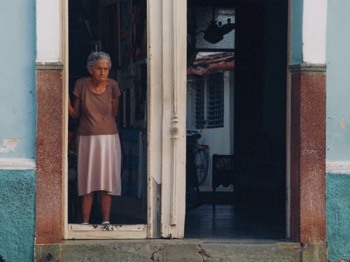Free Senior woman stands in a doorway, capturing a moment in urban life. Stock Photo