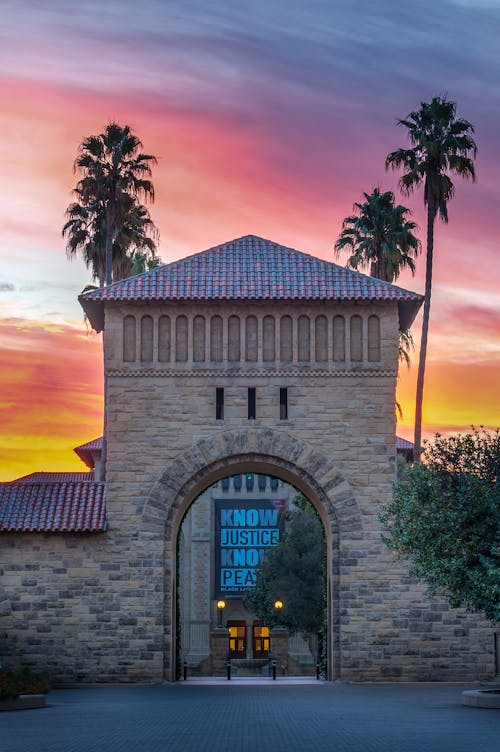 A sunset over a university building with palm trees