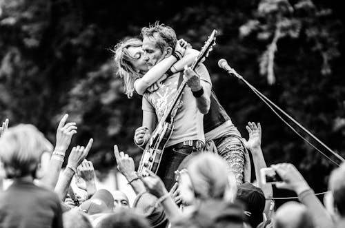 無料 ギターを弾く男性にキスする女性のグレースケール写真 写真素材