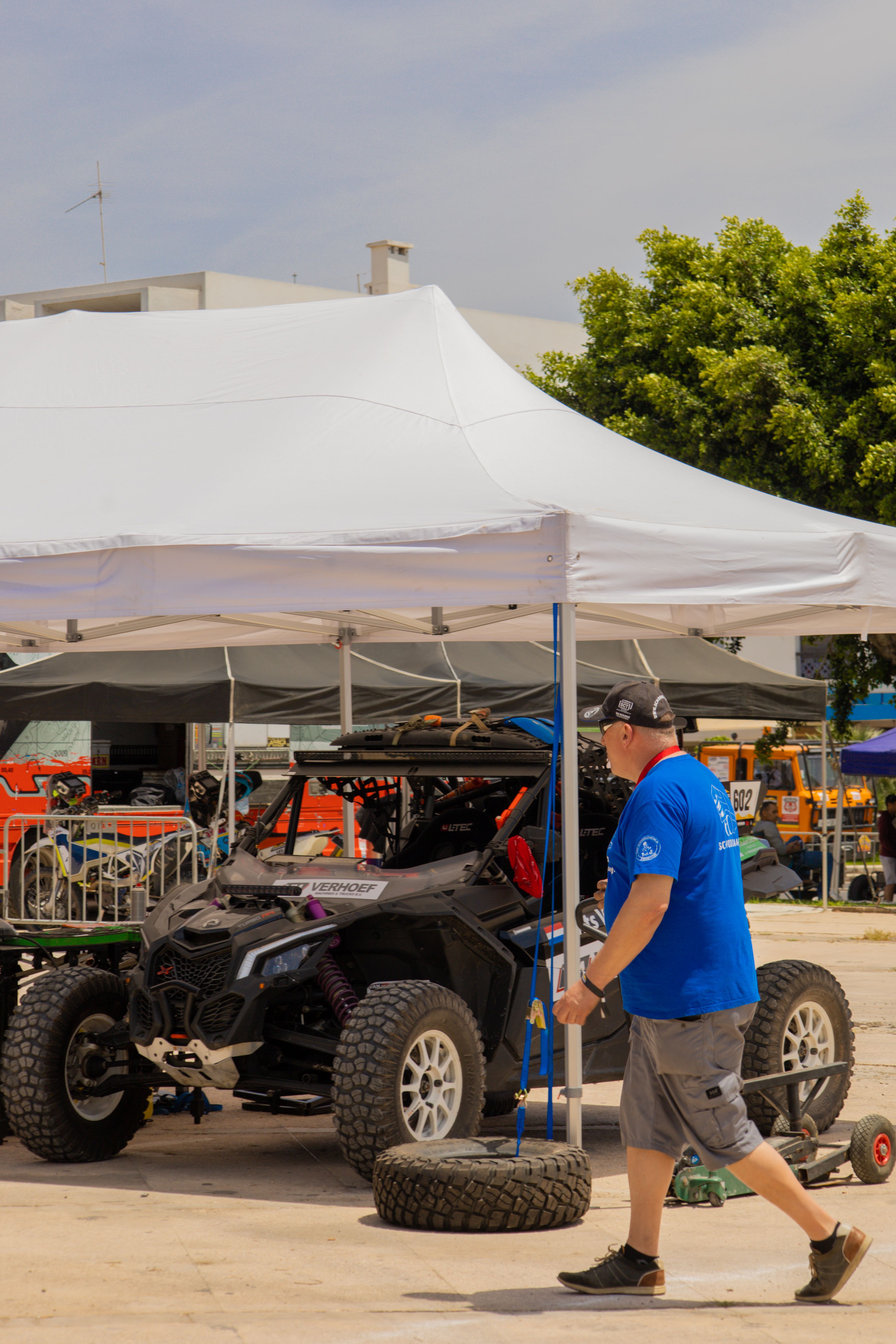 Man preparing vehicle for off-road race under canopy in Agadir, Morocco.