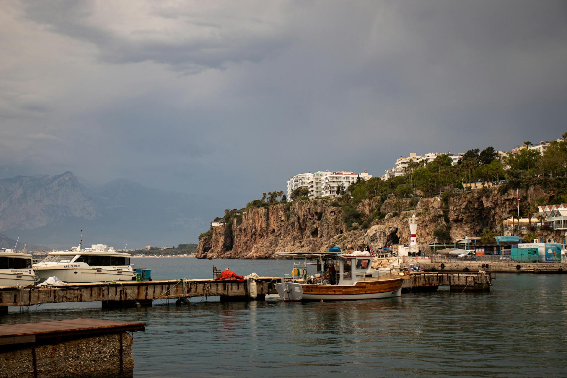 Serene marina view in Antalya, Turkey with boats, cliffs, and buildings overlooking the calm sea.