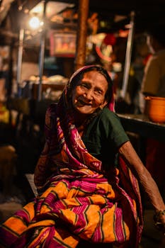 这幅迷人的肖像描绘了一位身着传统服装、在色彩缤纷的市场中快乐微笑的老妇人