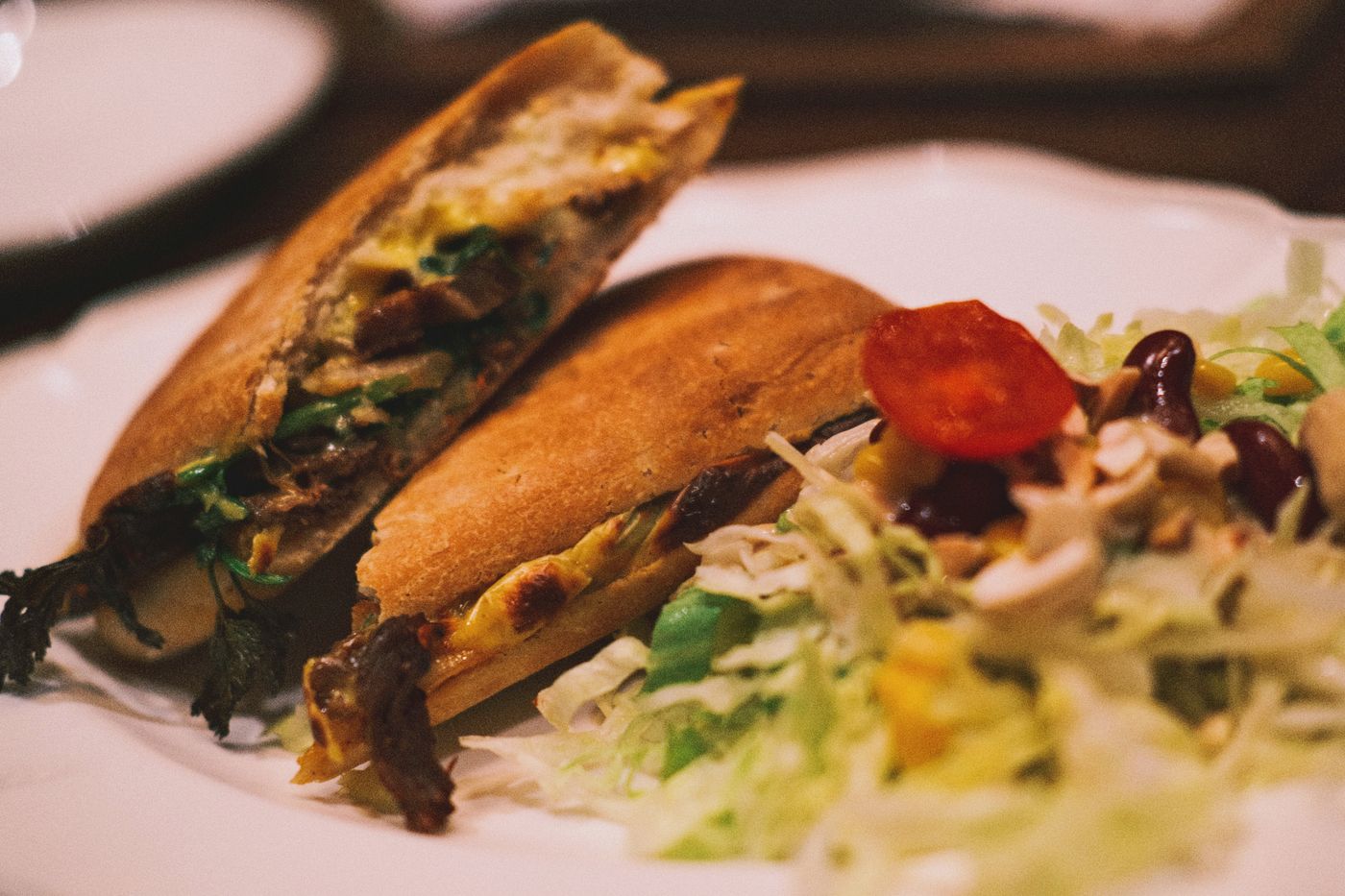 Close-up of a panini sandwich served with a fresh veggie salad on a plate.