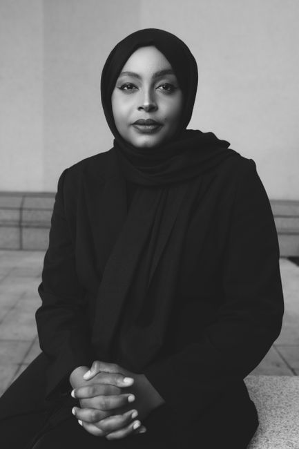 Black and white portrait of woman wearing a hijab, exuding elegance and grace indoors.