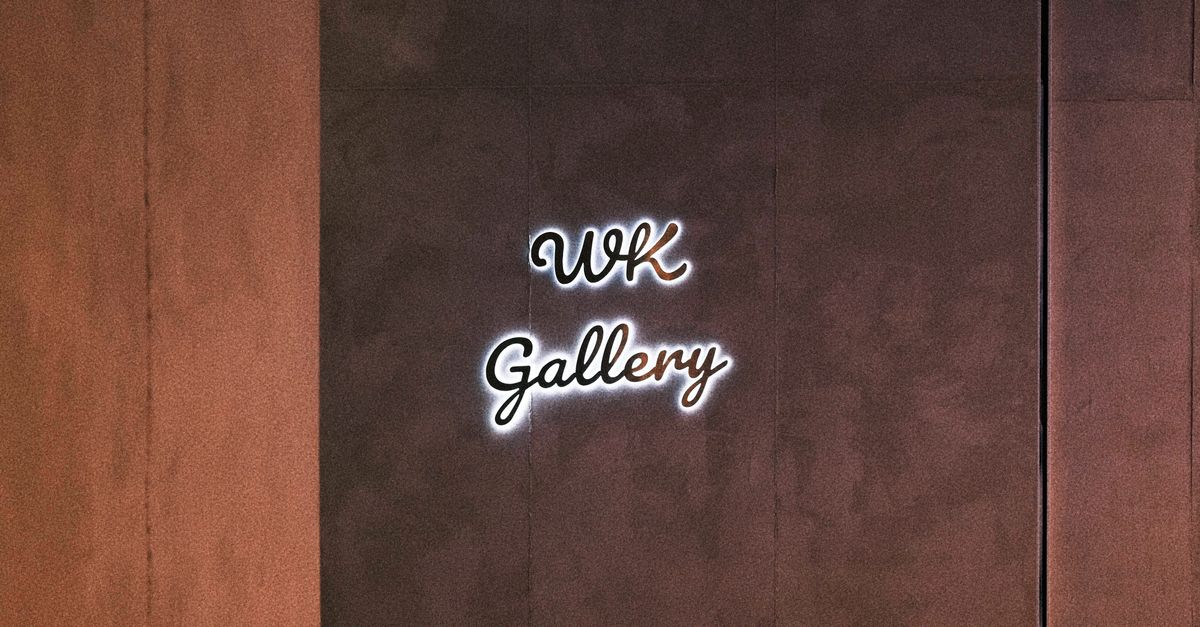 Close-up of illuminated WK Gallery sign on a textured brown wall, perfect for art exhibitions.