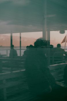 Silhouetted ferry passengers with reflections at twilight, capturing tranquil travel vibes.