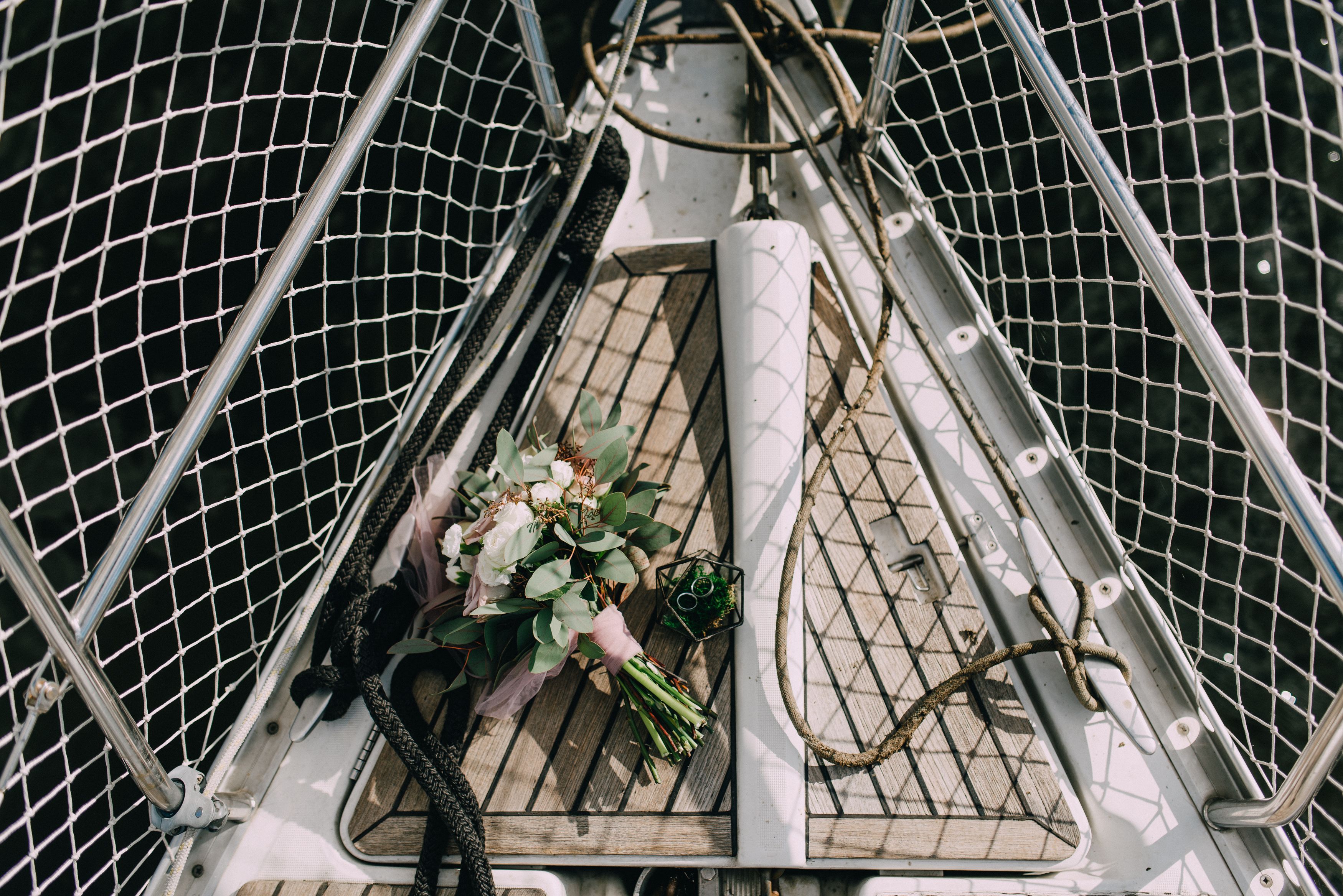 A beautiful bridal bouquet placed on a sailboat deck, featuring flowers and wedding rings.