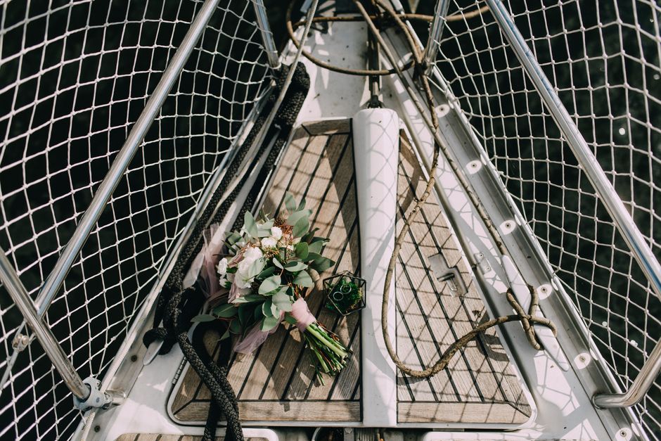 A beautiful bridal bouquet placed on a sailboat deck, featuring flowers and wedding rings.