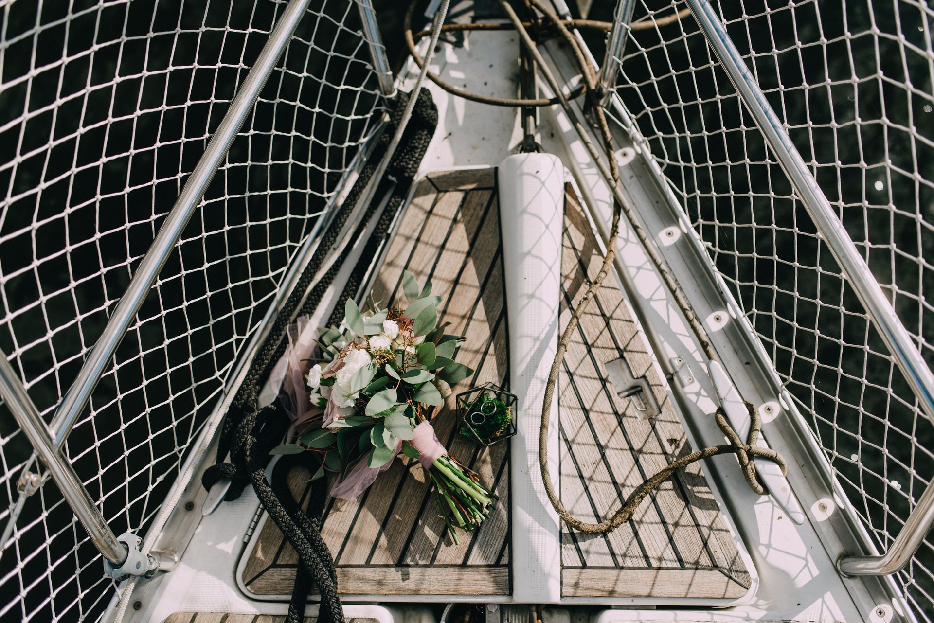 A beautiful bridal bouquet placed on a sailboat deck, featuring flowers and wedding rings.