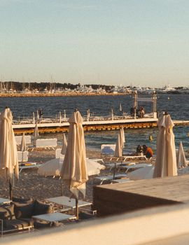 Relaxing Cannes beachfront scene with chairs, umbrellas, and a marina backdrop.