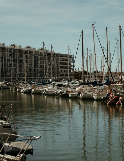 Free Idyllic marina in Cannes with yachts, clear skies, and residential buildings reflecting on calm waters. Stock Photo