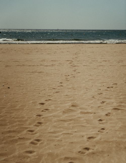 Free Serene sandy beach with footprints leading to the sea under a clear sky, Barcelona. Stock Photo