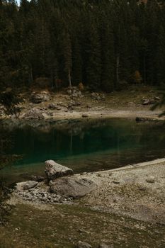 Discover the serene beauty of Karersee Lake in Trentino, Italy, surrounded by lush forests and rocky shores.