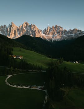 Spectacular aerial view of Bolzano's mountain landscape with lush valleys and rugged peaks under a clear sky.