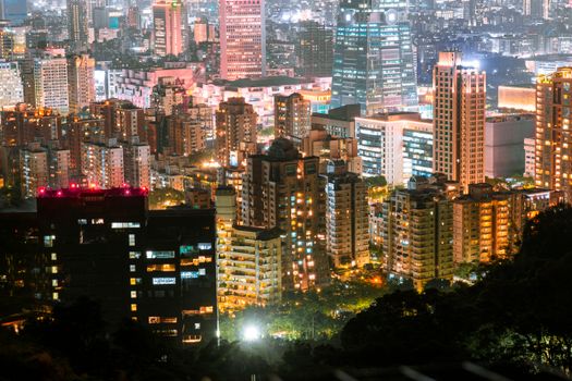 Aerial view of a vibrant cityscape at night with illuminated skyscrapers and bustling streets.