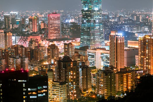 Aerial view of a vibrant city skyline at night, featuring illuminated skyscrapers and bustling urban life.