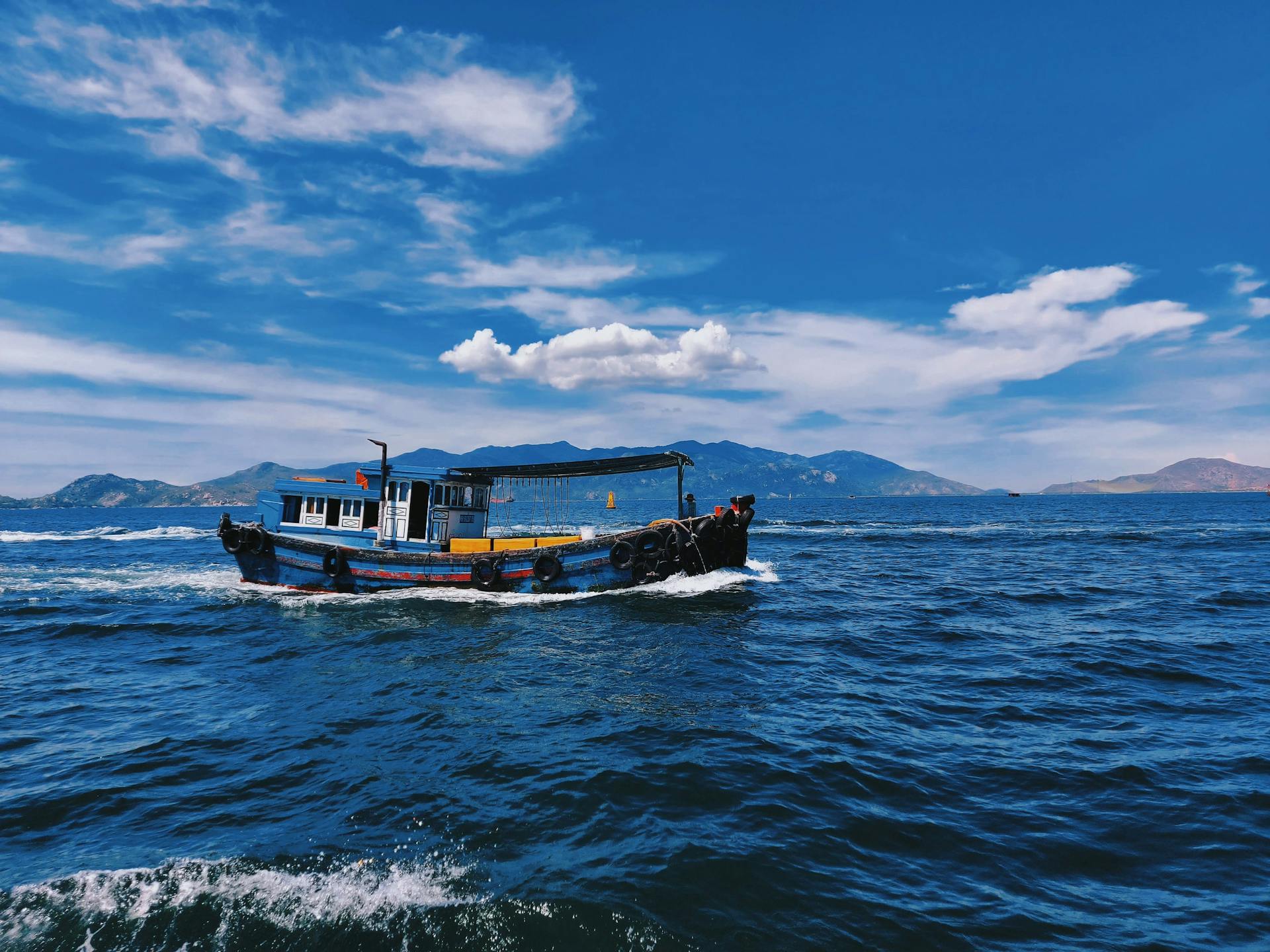 A picturesque view of a traditional fishing boat sailing through the vibrant waters of Cam Ranh Bay, Vietnam.