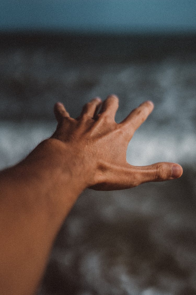 Photo Of An Open Hand With The Sea In The Background 