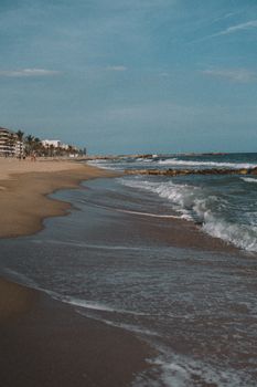 Peaceful waves and sandy beach along the Barcelona coastline, showcasing resort scenery.