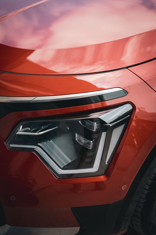 Free Detailed view of a red car's headlight, showcasing sleek modern automotive design. Stock Photo