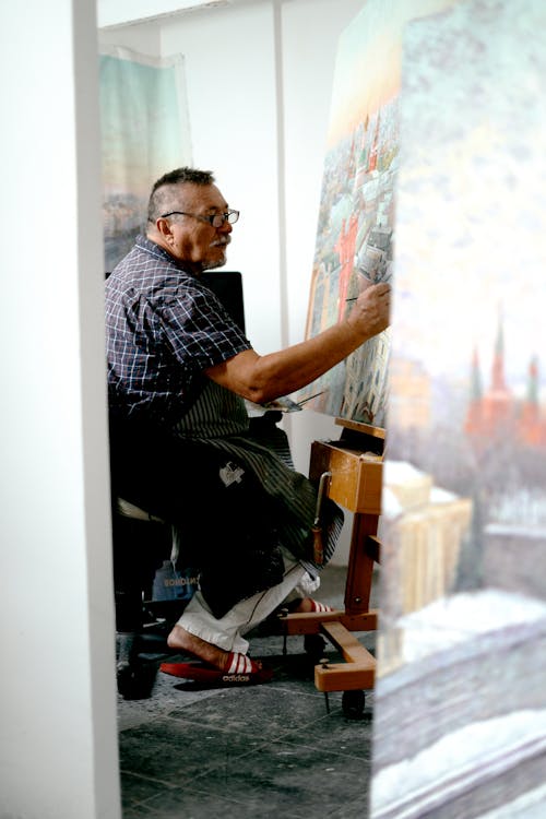 Photo of a Man Painting on a Canvas