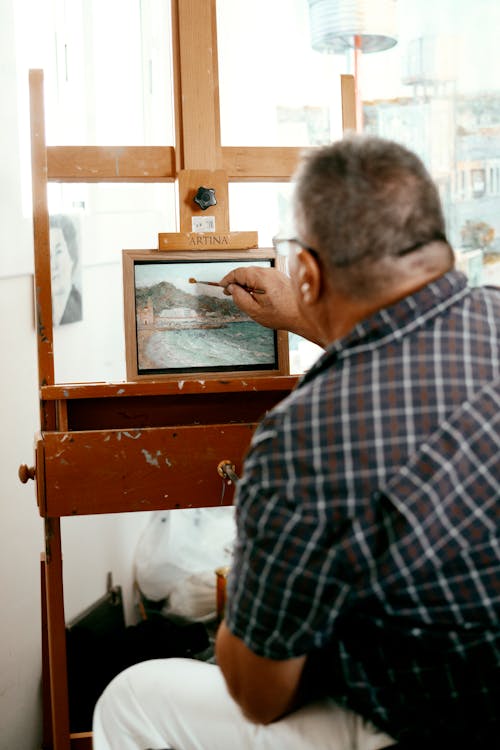 Photo of a Man Painting on a Small Canvas
