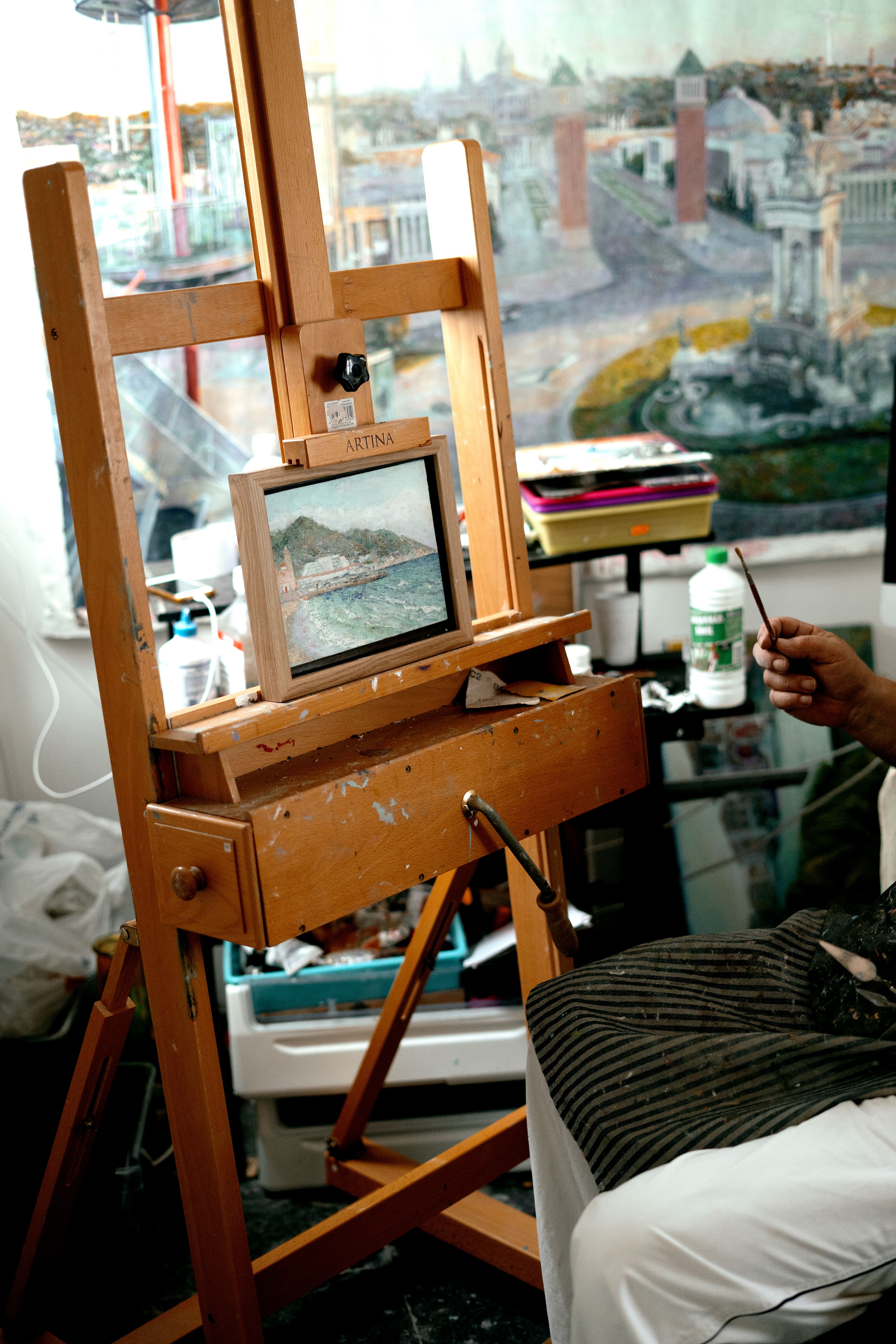 Artist painting landscape on easel in a Barcelona studio, showcasing creative process.
