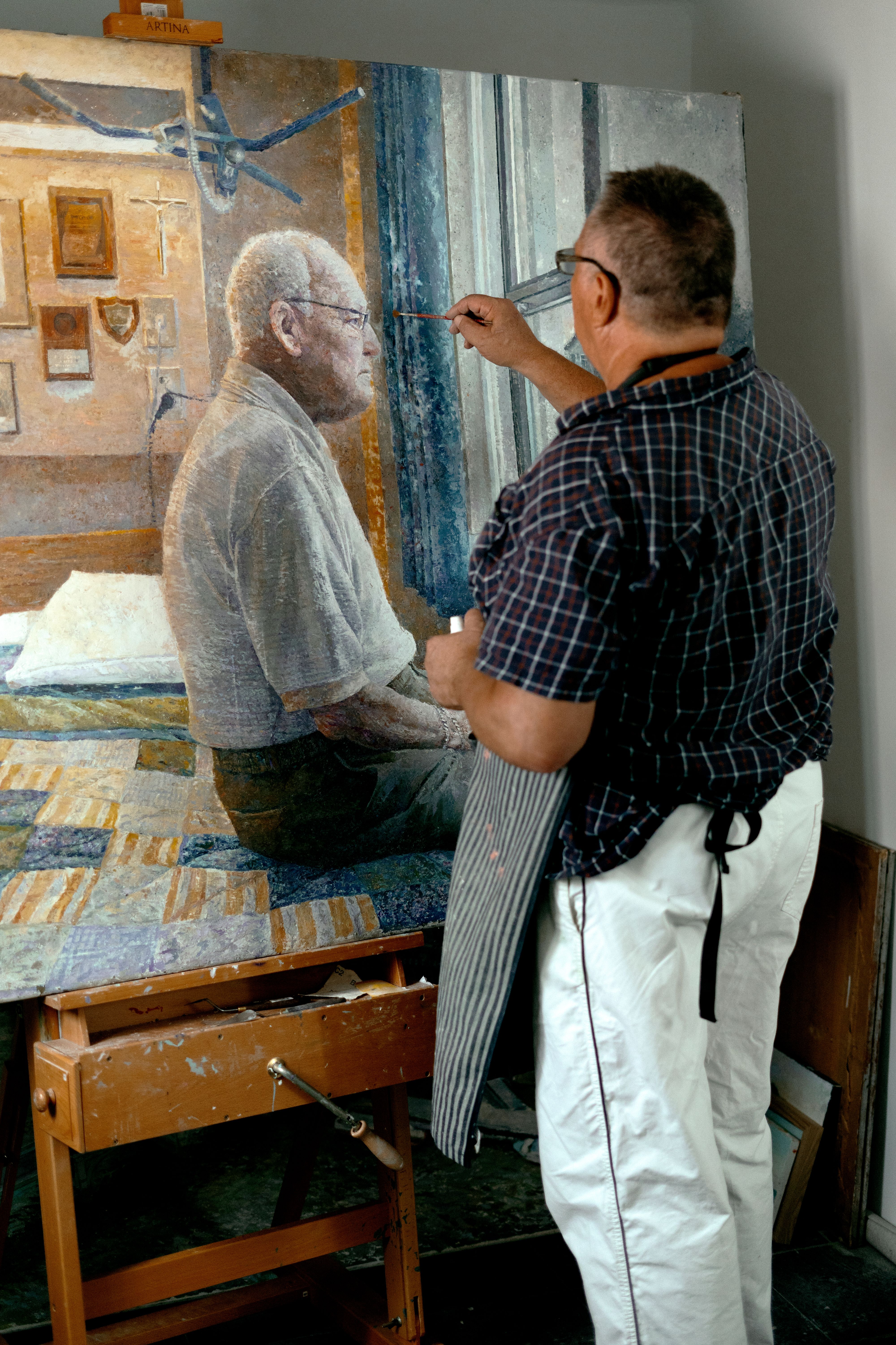 A skilled artist paints an elderly man in a serene studio in Barcelona.