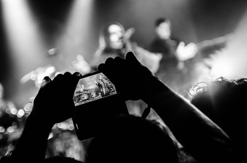 Grayscale Photography of Person Taking Picture of Band