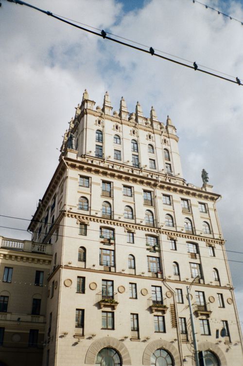 Free Low-angle view of a sunlit historic building in Minsk, showcasing architectural details against a cloudy sky. Stock Photo
