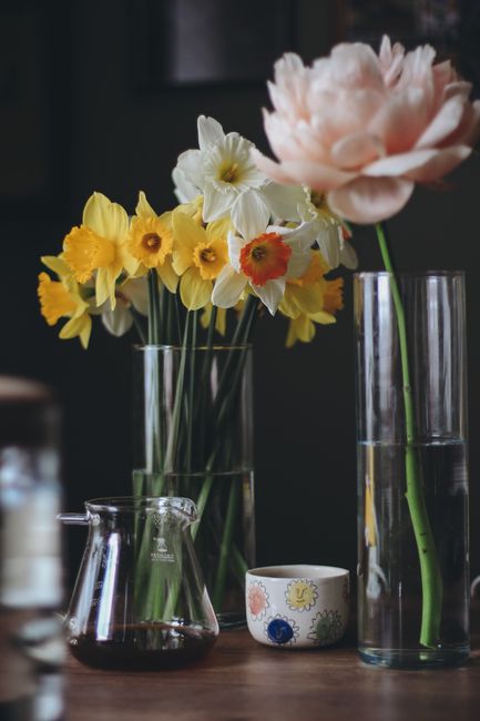 Beautiful close-up of colorful spring flowers in glass vases on a wooden table.
